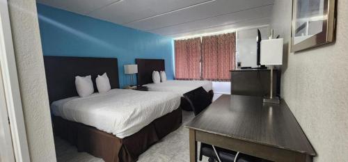 a hotel room with two beds and a desk at Travelodge by Wyndham Kingsland GA in Kingsland