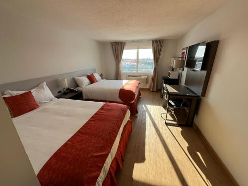 a hotel room with two beds and a television at The Lodge Inn in Edmonton