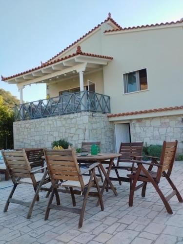 a wooden table and chairs in front of a house at Villa Elaida in Ermioni