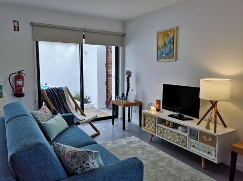 a living room with a blue couch and a tv at Furnas Springs in Furnas