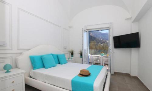 a white bedroom with a bed with a hat on it at Villa Dei SRLS in Positano - Camere in Positano
