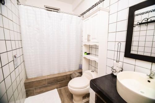 a white bathroom with a toilet and a sink at Hotel Villa del Lago in Flores