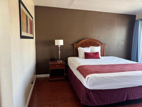 a hotel room with a bed with a red pillow at Holiday Lodge in Los Angeles