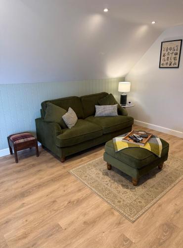 a living room with a green couch and a table at Minafon Loft in Meifod
