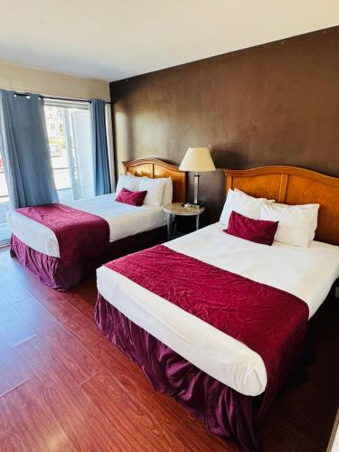a hotel room with two beds with red sheets at Holiday Lodge in Los Angeles