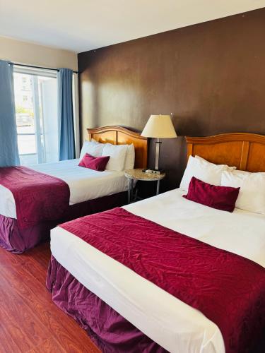 a hotel room with two beds with red sheets at Holiday Lodge in Los Angeles