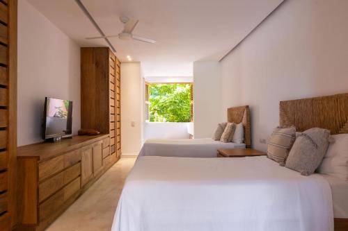 a bedroom with two beds and a flat screen tv at El Careyes Club & Residences in Careyes