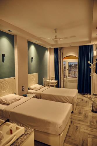 two beds in a hotel room with blue curtains at Town Hotel- Hurghada in Hurghada