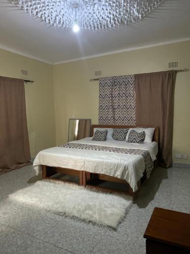 Un dormitorio con una cama y una lámpara de araña. en Mable Home, en Mzuzu
