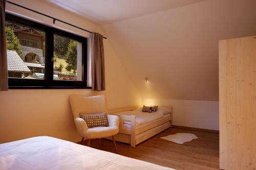 a bedroom with a cat sitting on a couch and a chair at BINDT chalets in Hnilčík