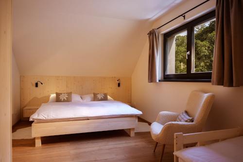 a bedroom with a bed and a window and a chair at BINDT chalets in Hnilčík