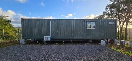 a green shipping container sitting on top of gravel at Green Discovery's Birds' Nests in Henrietta