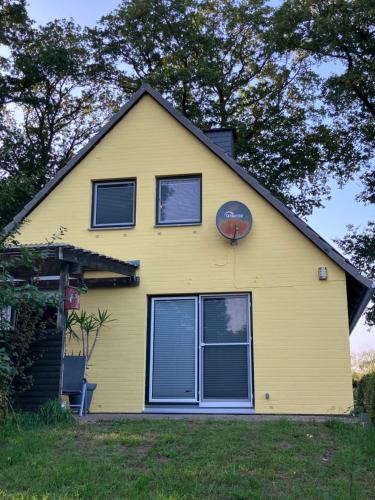 a yellow house with a clock on the top of it at Haus Wald und Wiese Wohnung Wald in Ehndorf