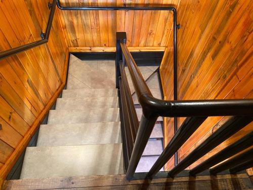 a staircase in a wooden building with a black rail at Cabañas Santa María in Pichilemu
