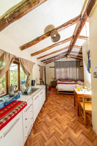 a kitchen with white cabinets and a table and a bed at Eco Lodge Cabañas con Piscina in Urubamba