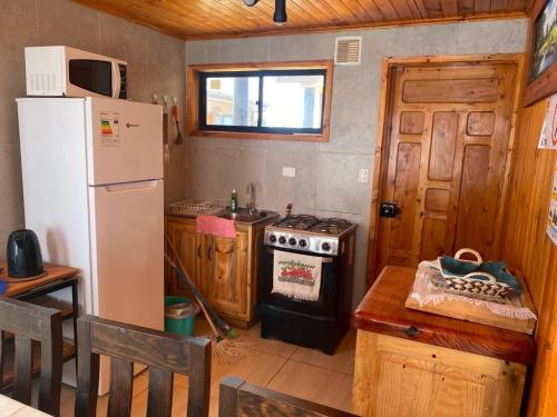 a kitchen with a refrigerator and a stove at Cabañas Santa María in Pichilemu