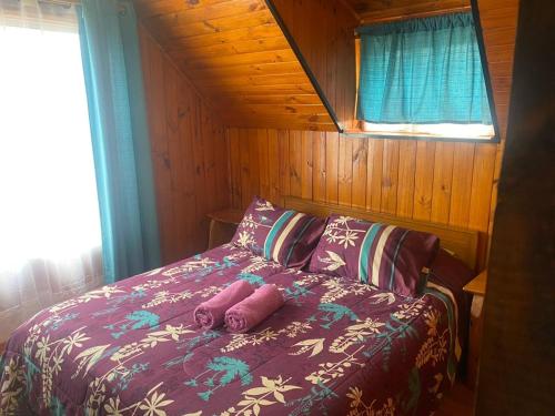 a bed with two pillows on it in a room at Cabañas Santa María in Pichilemu