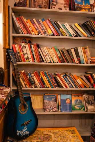 a guitar in a book shelf with books at Jaisalmer Elite Castle in Jaisalmer
