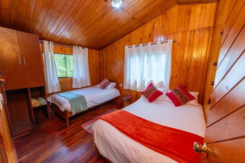 a bedroom with two beds in a wooden cabin at Eco Lodge Cabañas con Piscina in Urubamba