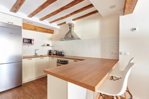 cocina con armarios blancos y encimera de madera en Balcon del Encierro, en Pamplona