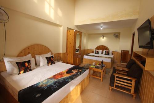 a hotel room with a bed and a television at Hotel Purnima Kasol in Kasol
