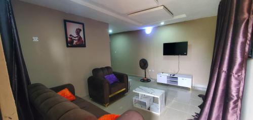 a living room with a couch and a tv at 2 bedroom service apartment in Ibadan