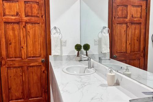 a bathroom with a sink and a wooden door at Hotel Termales La Montaña in Ahuachapán