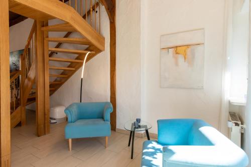 a living room with blue chairs and a staircase at Denkmalgeschütztes Fachwerkhaus im Zentrum mit Garage in Ibbenbüren