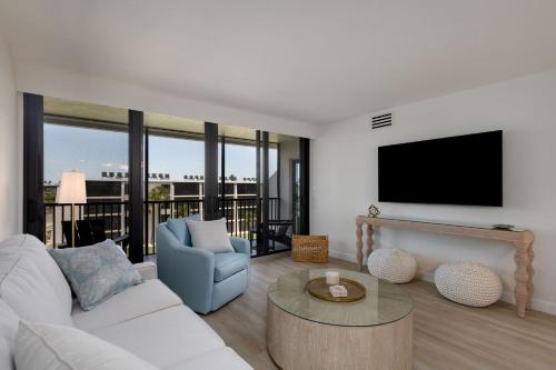 a living room with a white couch and a tv at Sundial F403 - Beach Bliss in Sanibel