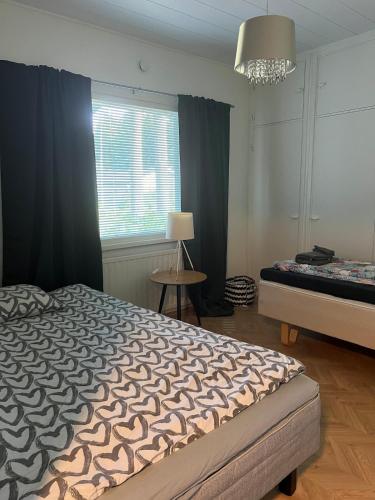 a bedroom with a bed and a window and a chandelier at Lemminkäinen in Kokkola