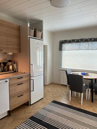 a kitchen with a white refrigerator and a table at Lemminkäinen in Kokkola