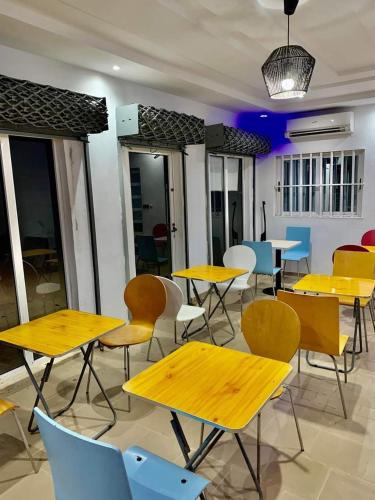 a cafeteria with yellow tables and chairs and tables and chairs at Bleu Marin Résidence hôtelière in Grand-Popo