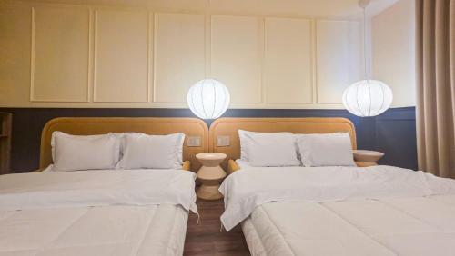 two beds in a room with white sheets and lights at Hotel Acqua Medellín in Medellín