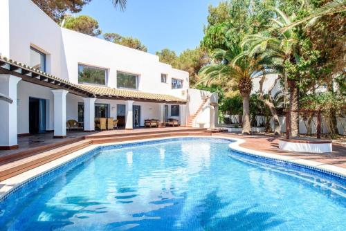 a swimming pool in front of a house with palm trees at Villa Mar de Luz - Seafront Residence in Santa Eularia des Riu