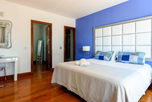 a bedroom with a large bed with blue walls at Villa Mar de Luz - Seafront Residence in Santa Eularia des Riu