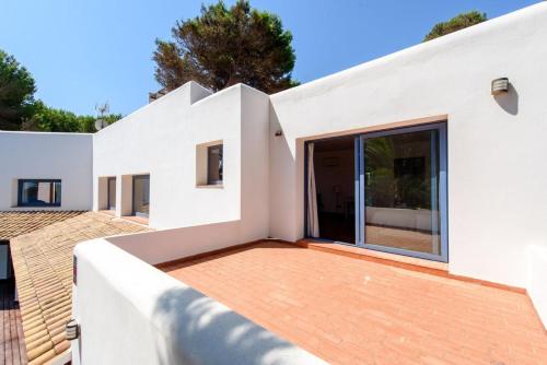 a white house with a deck and large windows at Villa Mar de Luz - Seafront Residence in Santa Eularia des Riu