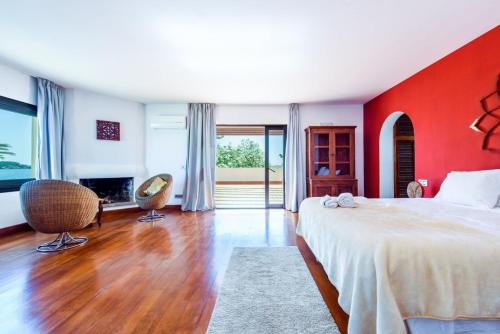 a bedroom with a large bed and a red wall at Villa Mar de Luz - Seafront Residence in Santa Eularia des Riu