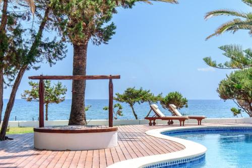 a swimming pool with a bench next to the ocean at Villa Mar de Luz - Seafront Residence in Santa Eularia des Riu