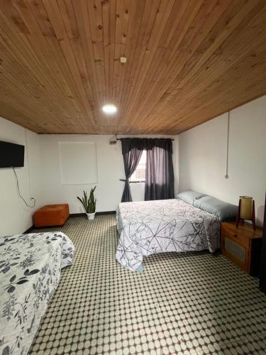 a bedroom with two beds and a wooden ceiling at El refugio santarrosano in Santa Rosa de Cabal