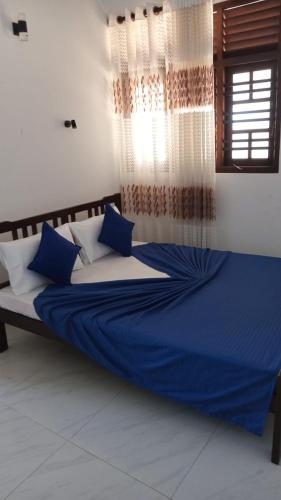 a bed with blue and white pillows in a room at Sunset Beach Villa in Galle