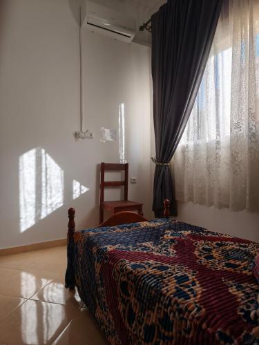 a bedroom with a bed and a chair and a window at Apartment in Villa - Tangier in Tangier