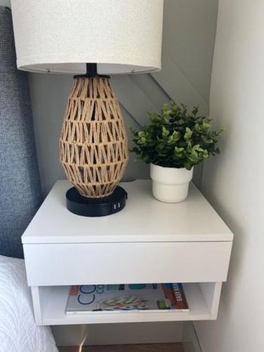 a white nightstand with a lamp and two plants on it at Serene Forest Retreat in Sooke