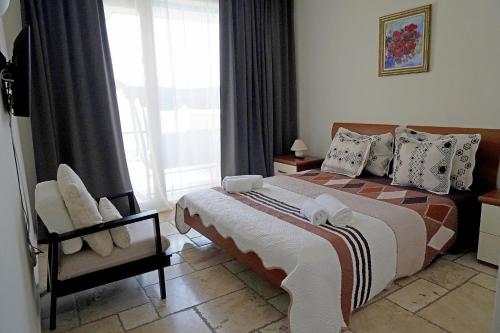 ein Schlafzimmer mit einem Bett und einem Stuhl und einem Fenster in der Unterkunft Kaliakria resort view of the black sea in Topola