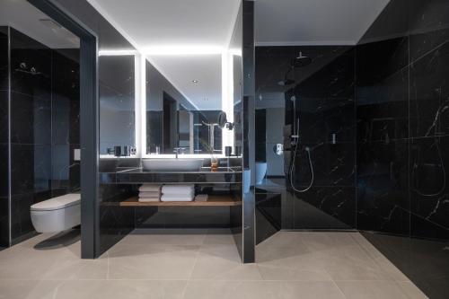 łazienka z umywalką, toaletą i lustrem w obiekcie Buff Hotel & Resort Konstanz w Konstancji
