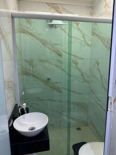 a bathroom with a glass shower and a sink at Guaru Inn Hostel in Guarulhos