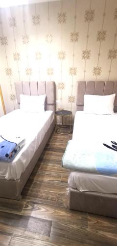two beds sitting in a room with wooden floors at Aladdin hotel Egypt badr in Badr