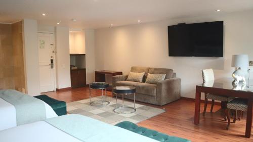 a living room with a couch a chair and a television at Hotel Portón de la Cabrera in Bogotá