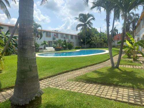a swimming pool in front of a building with palm trees at Casa en condominio 2R alberca compartida in Acapulco