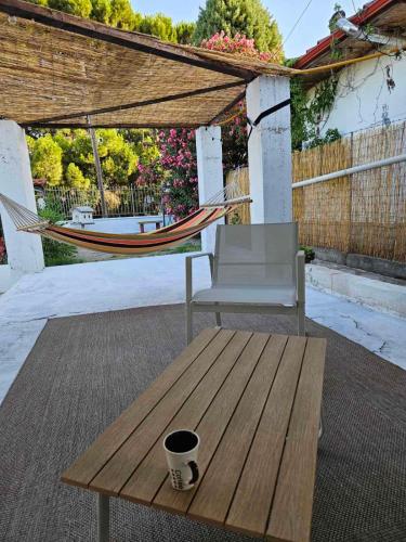 a hammock and a chair and a table on a patio at Villa Aspri in Nea Kalikratia