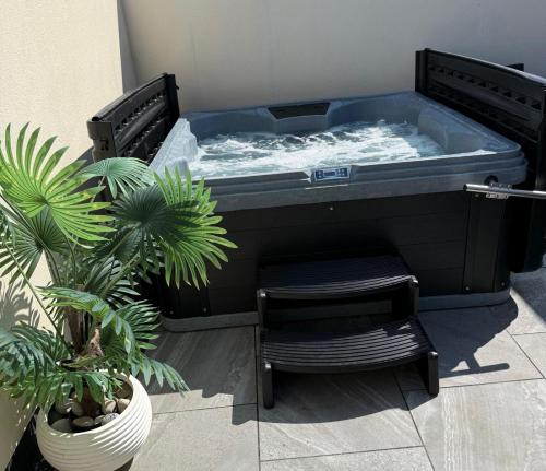 a soaking tub with a chair and a plant at Swish Luxury Holiday Apartments in Blackpool